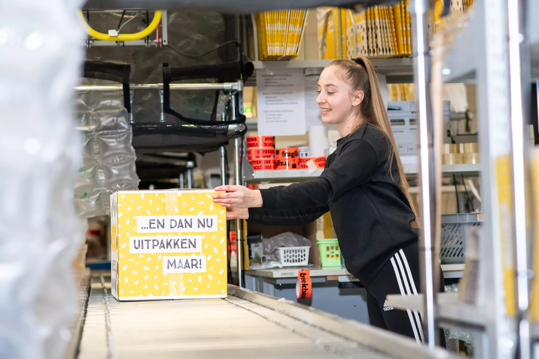 Man is vrolijk een winkelschap met kleding aan het inruimen.