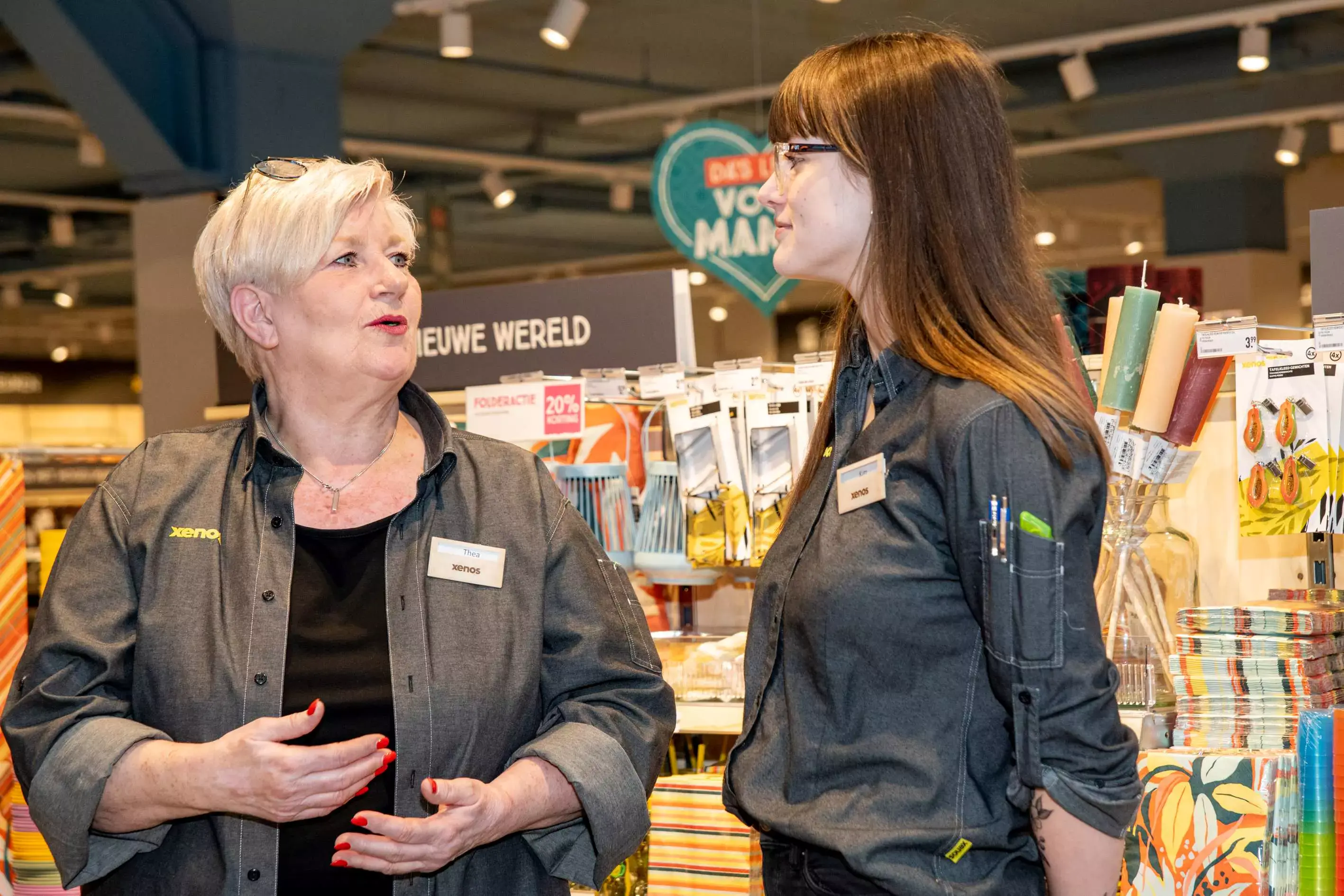Man is vrolijk een winkelschap met kleding aan het inruimen.